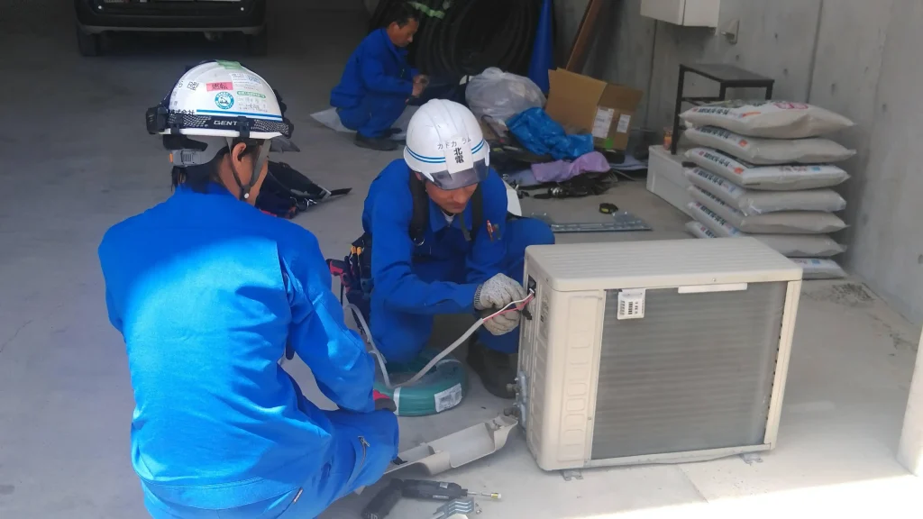 Automotive technicians performing hands-on maintenance and repair work on an air conditioning system.