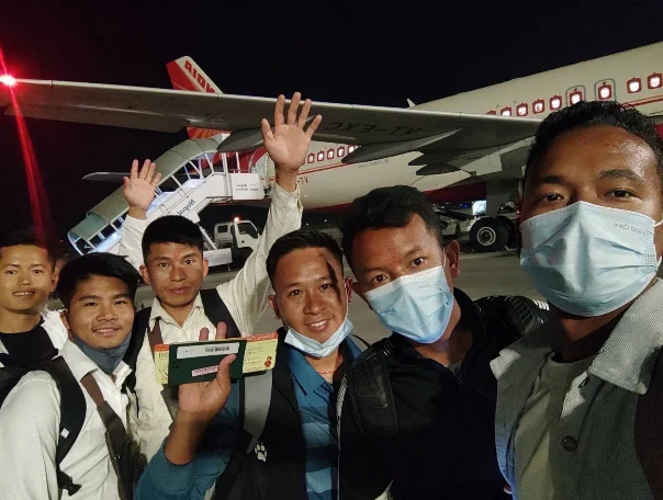 Trainees posing for a group photo with an airplane before departing for Japan.